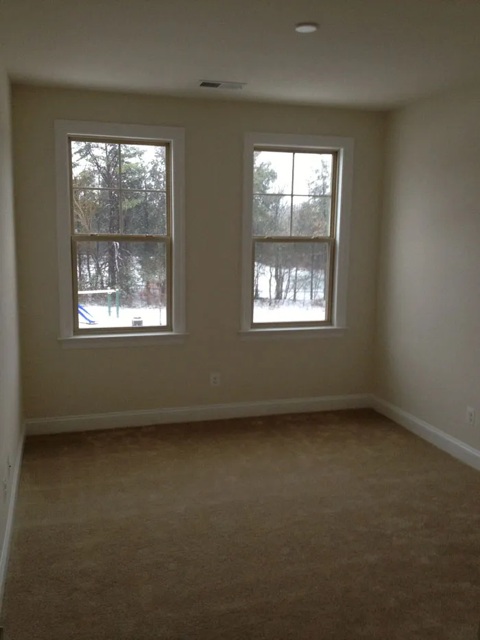 The original room with beige carpet and walls