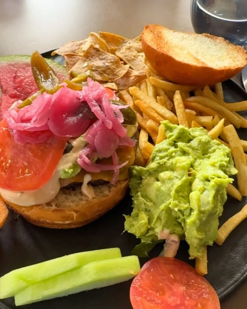 A cheeseburger that you can barely see through the toppings and guacamole.